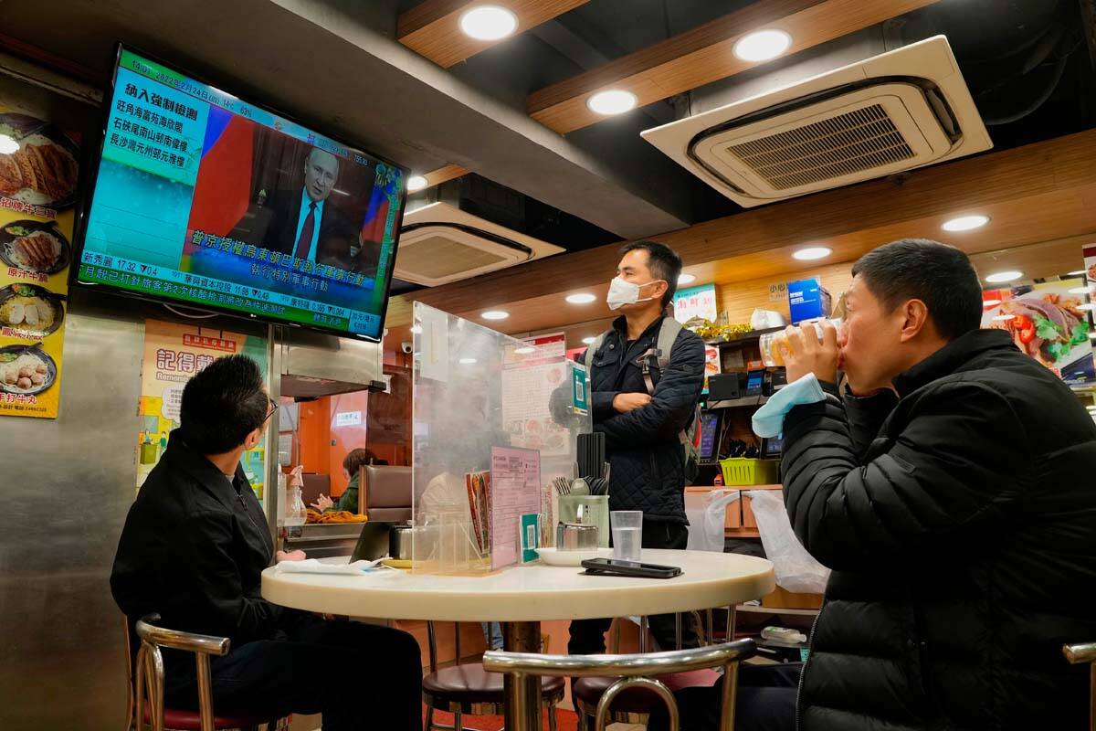 People watch a TV program broadcasting the news of Russian troops that have launched their atta ...