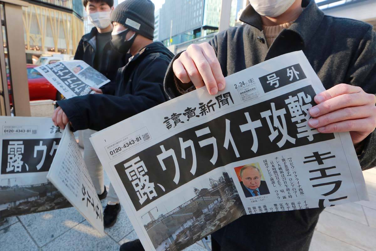 Pedestrians receive copies of the extra issue reporting on Russia’s military actions in ...