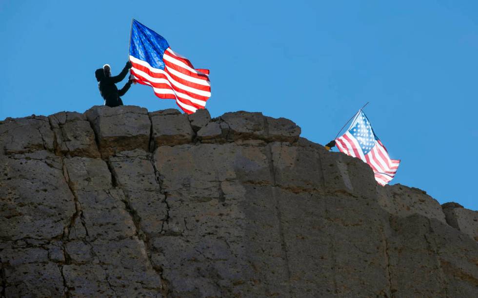 Several supporters fly American flags from atop of a ridge above the I-40 as The People’ ...