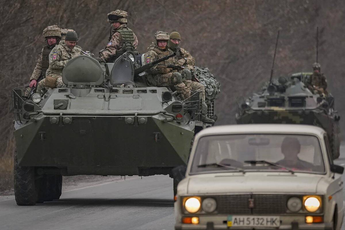 Ukrainian servicemen sit atop armored personnel carriers driving on a road in the Donetsk regio ...