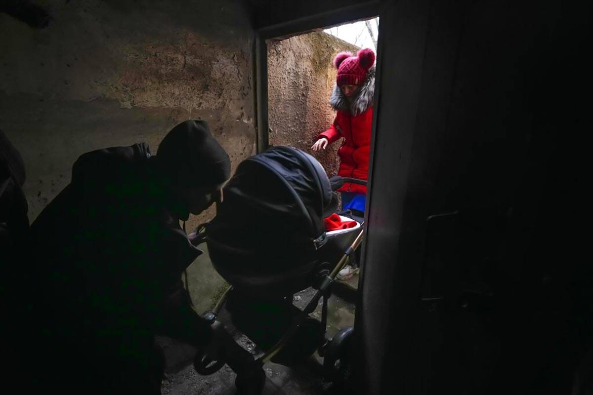 A couple enter a shelter with a baby in a stroller during Russian shelling outside Mariupol, Uk ...