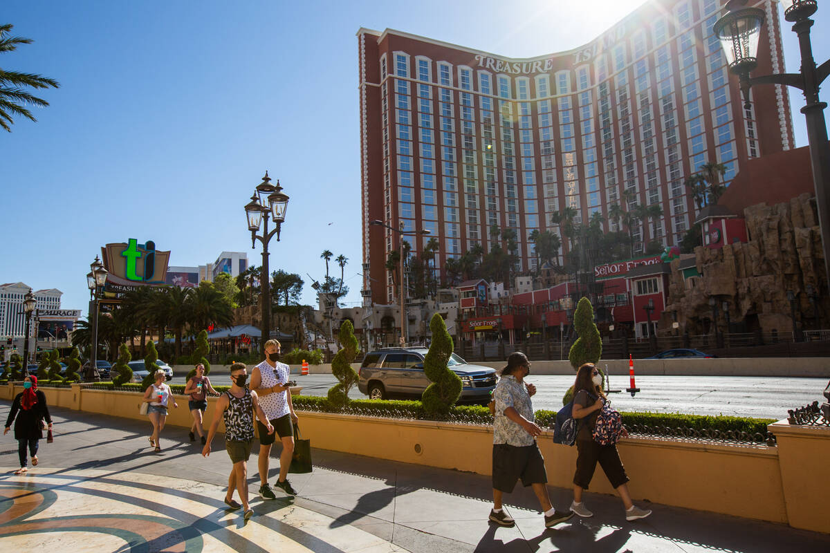 People walk down the Strip in front of Treasure Island in Las Vegas on Friday, July 3, 2020. Ph ...