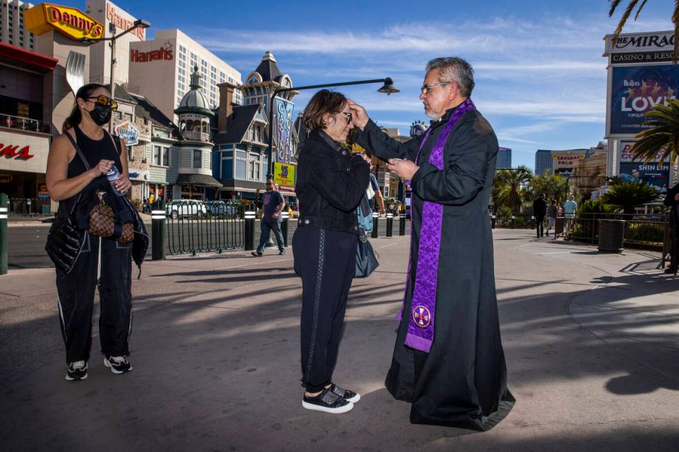 (From right) Priest Jorge Hernandez places ashes on the forehead of Lizette Maldonado from Puer ...