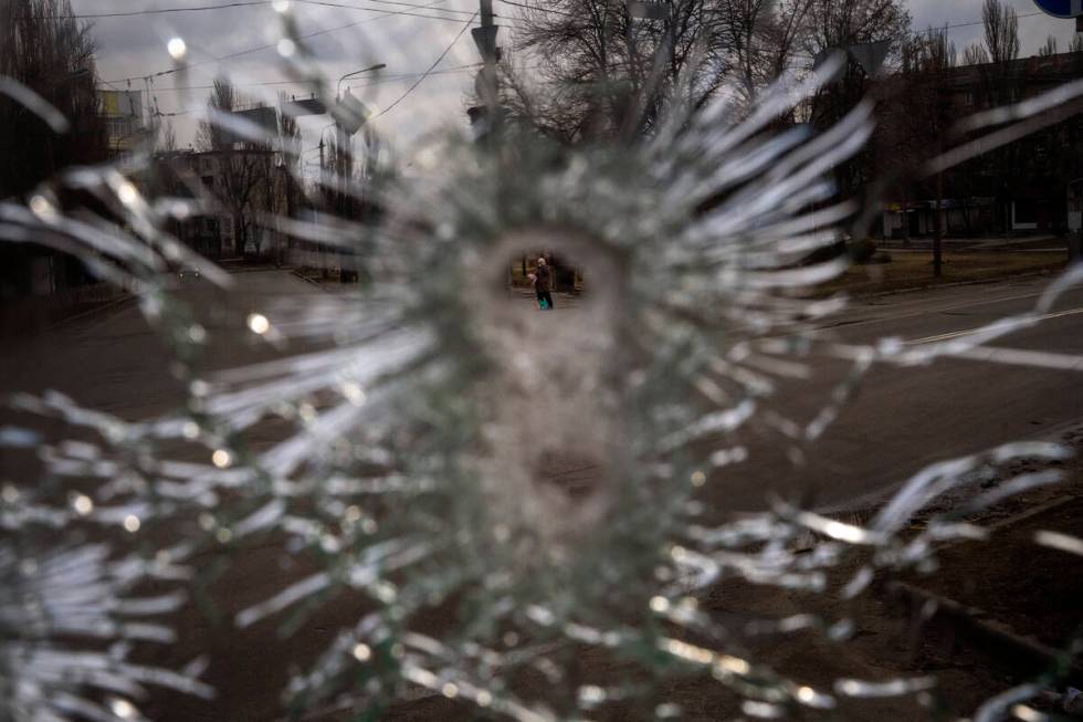 A man is seen through a bullet hole of a machine-gunned bus after an ambush in the city of Kyiv ...