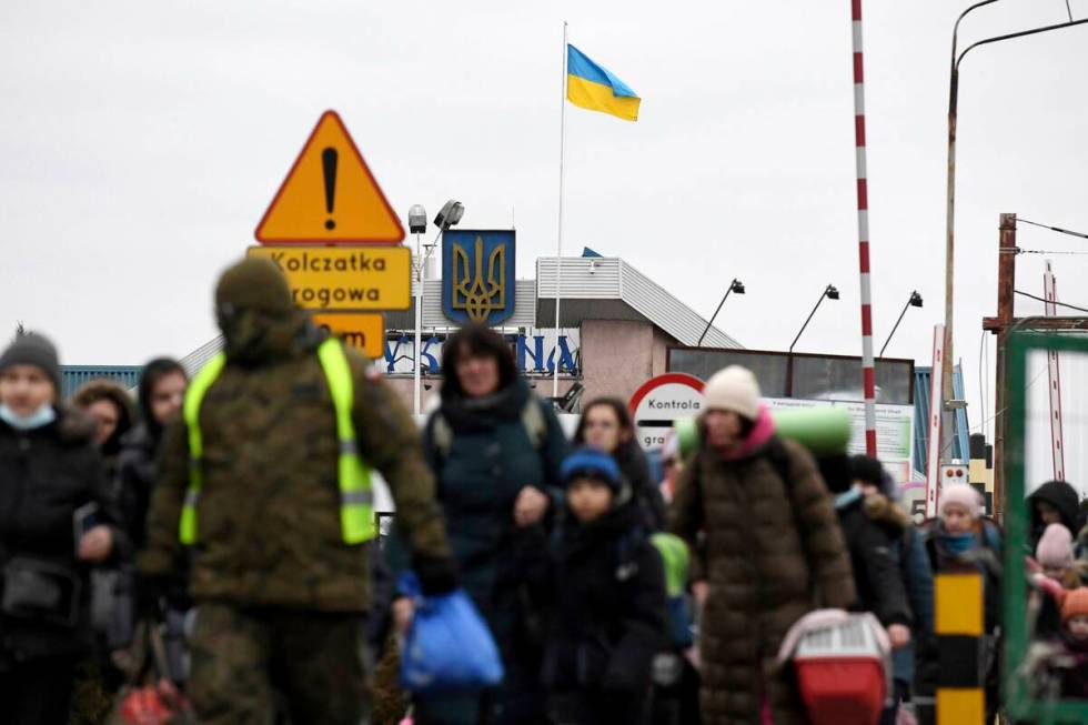 A Ukrainian flag flaps in the wind as people, fleeing Ukraine, cross at the Ukrainian-Polish bo ...