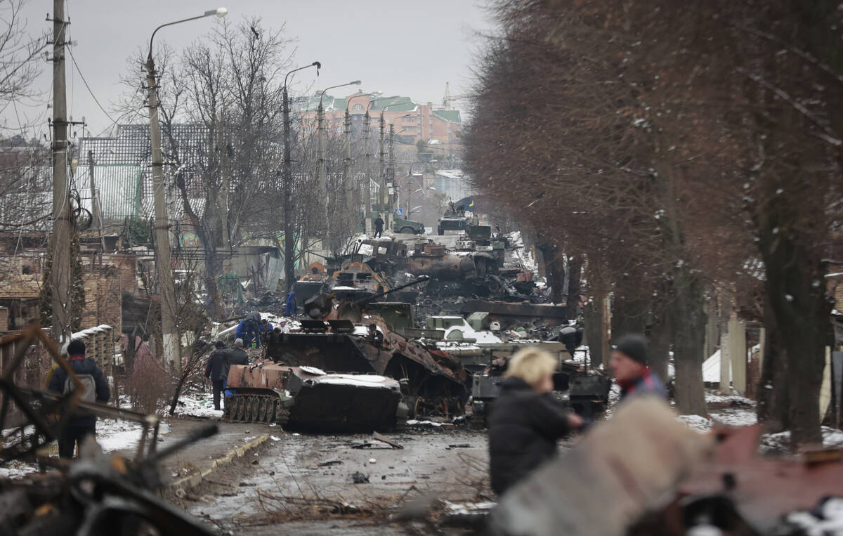 People look at the gutted remains of Russian military vehicles on a road in the town of Bucha, ...