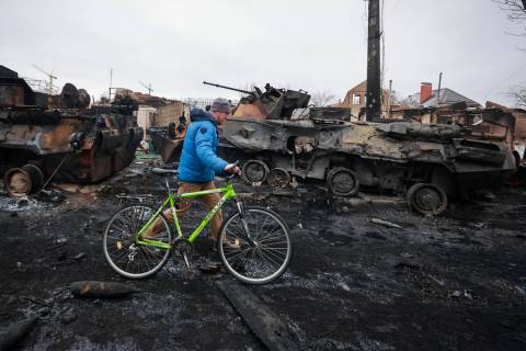 A man walks past the remains of Russian military vehicles in Bucha, close to the capital Kyiv, ...