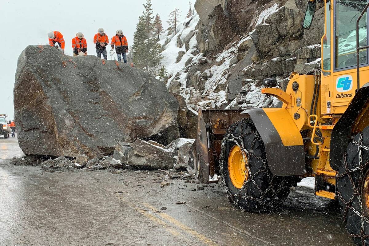 this photo provided by Caltrans, a crew places explosives into a large boulder that fell onto U ...