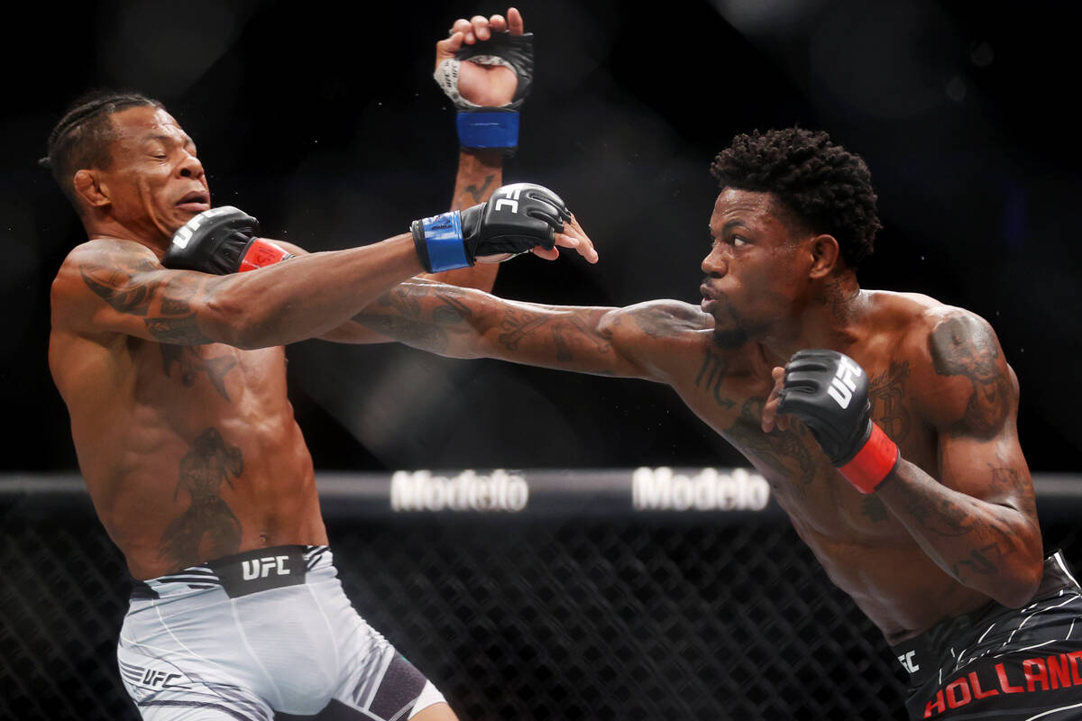 Kevin Holland, right, connects a punch against Alex Oliveira in the first round of an UFC 272 w ...
