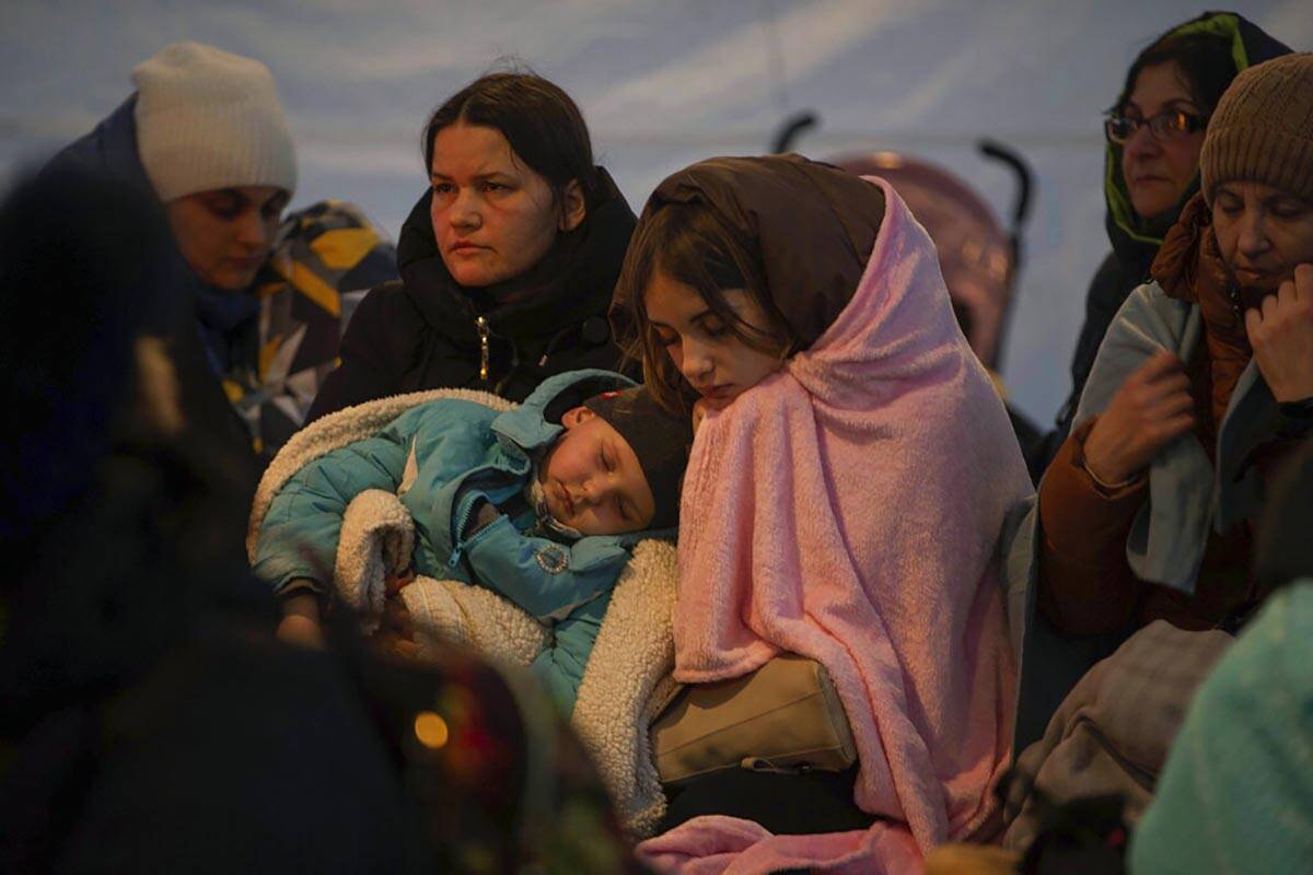 Refugees, mostly women with children, rest inside a tent after arriving at the border crossing, ...