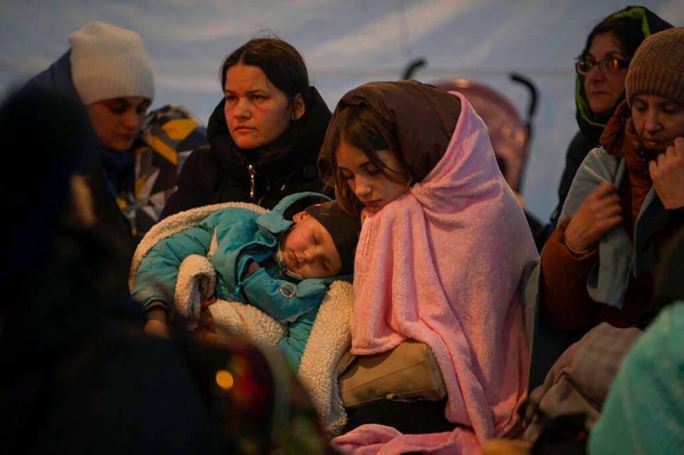 Refugees, mostly women with children, rest inside a tent after arriving at the border crossing, ...