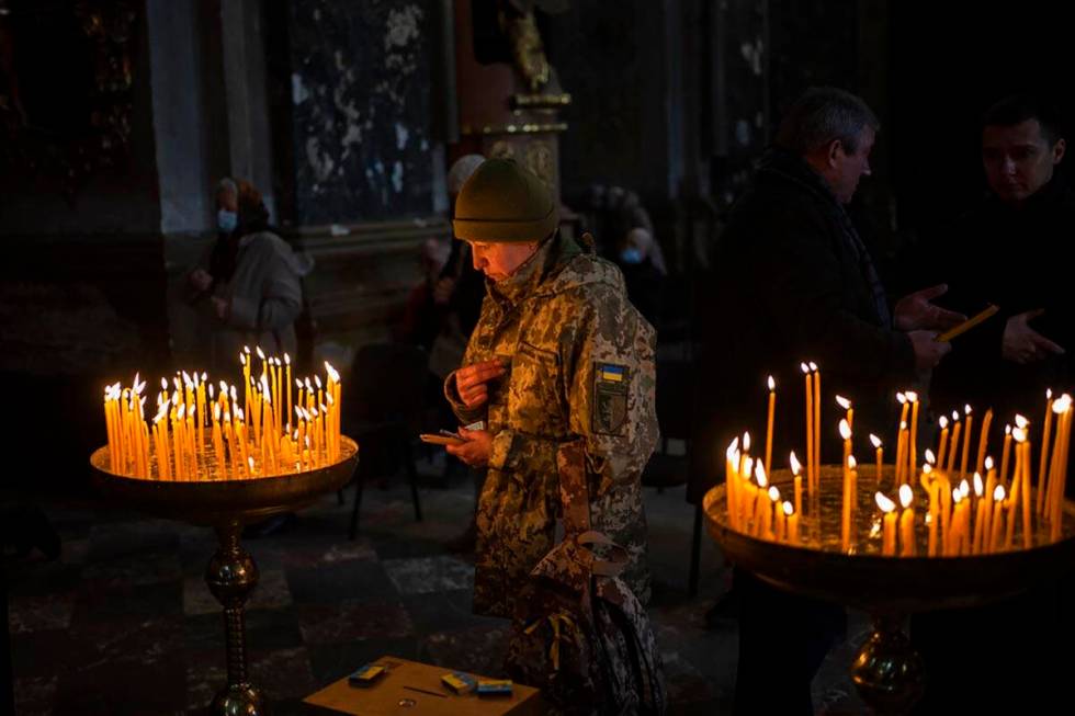 A Ukrainian woman dressed in military attire prays inside the Saints Peter and Paul Garrison Ch ...