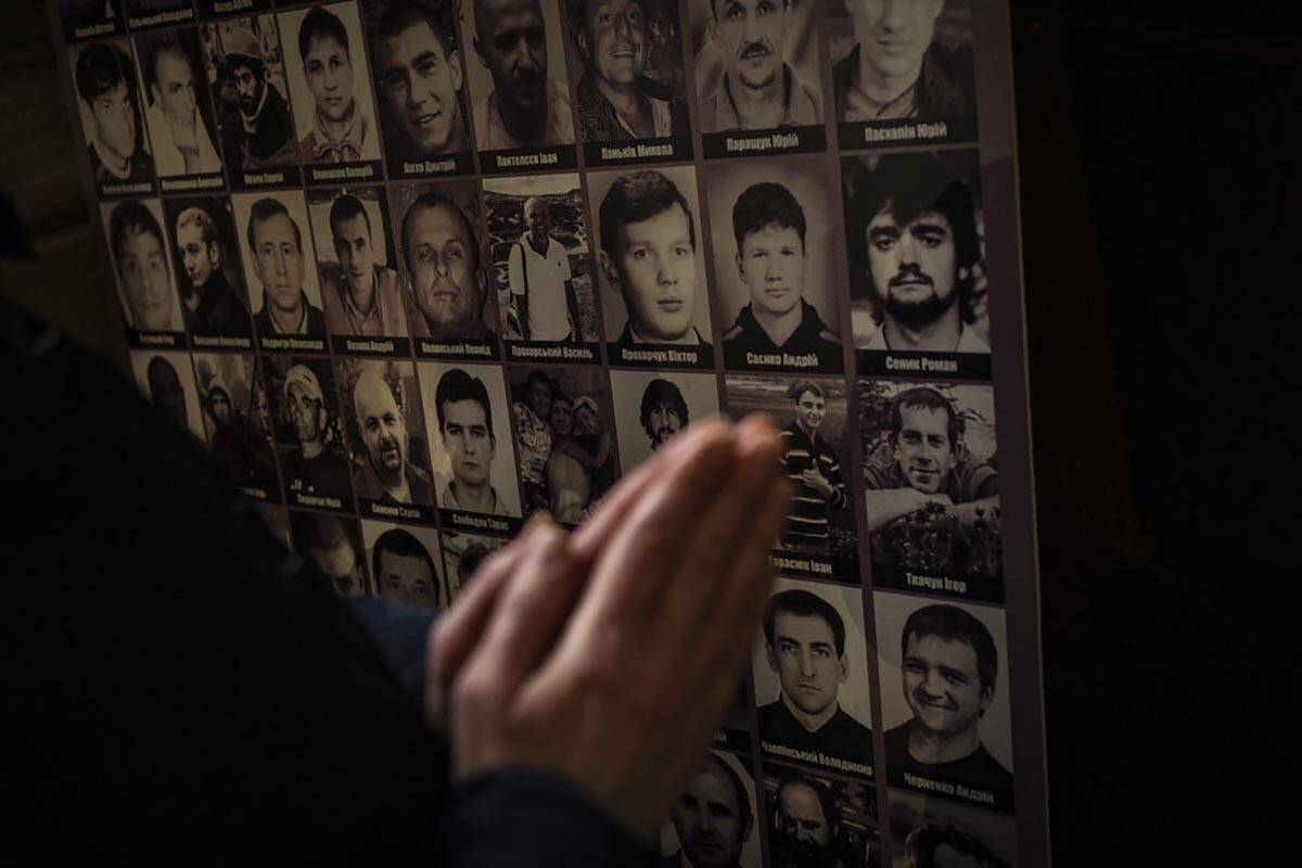 A Christian worshiper prays in front of pictures of fallen soldiers at the Saints Peter and Pau ...