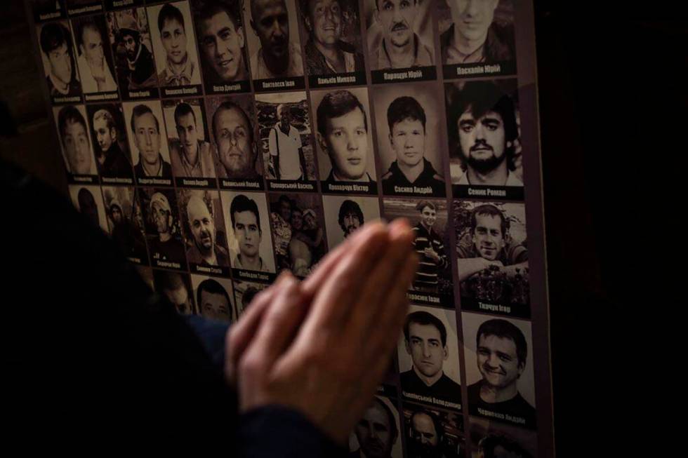 A Christian worshiper prays in front of pictures of fallen soldiers at the Saints Peter and Pau ...