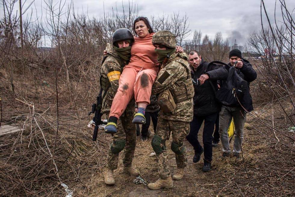 A woman carried by Ukrainian soldiers crosses an improvised path while fleeing the town of Irpi ...