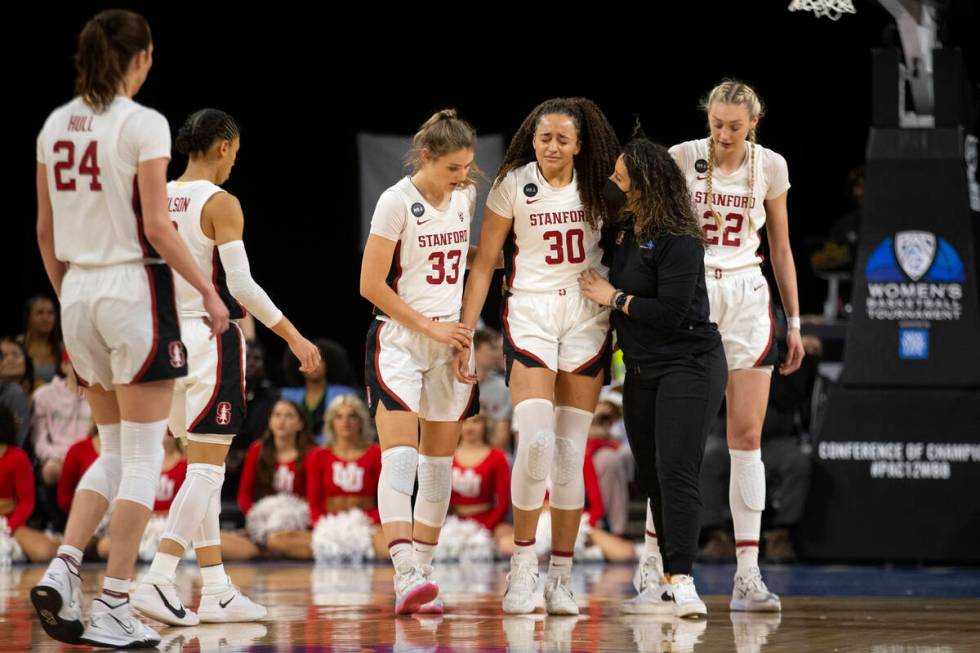 Stanford guard Haley Jones (30) walks off the court with an injury, flanked by guard Hannah Jum ...