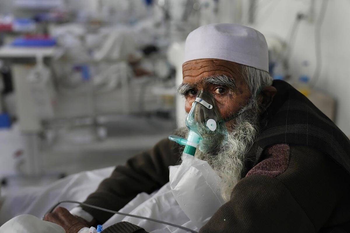 FILE - A patient infected with the coronavirus sits on a bed in the intensive care unit of the ...