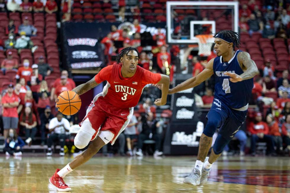 UNLV Rebels forward Donovan Williams (3) dribbles up the court while Nevada Wolf Pack guard Des ...