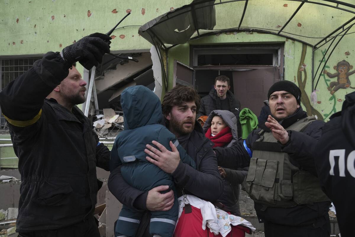 A man carries his child away from the damaged by shelling maternity hospital in Mariupol, Ukrai ...