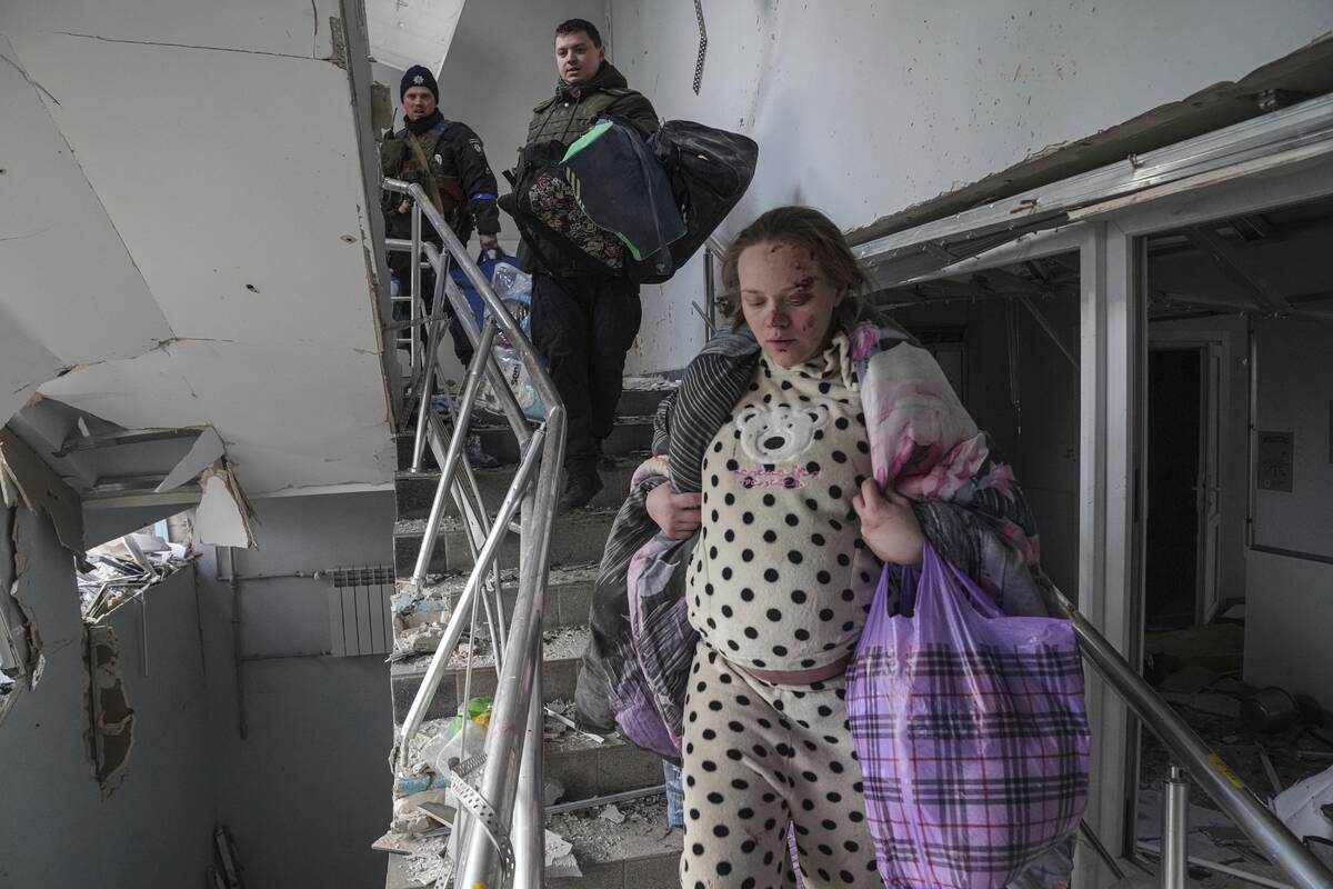 An injured pregnant woman walks downstairs in the damaged by shelling maternity hospital in Mar ...