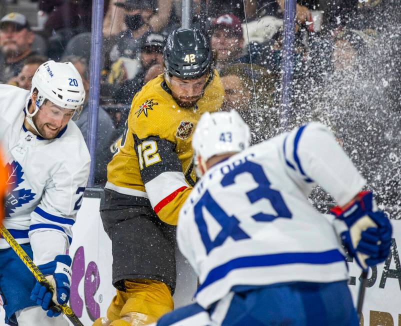 Ice is kicked up as Golden Knights defenseman Daniil Miromanov (42) battles for the puck with T ...