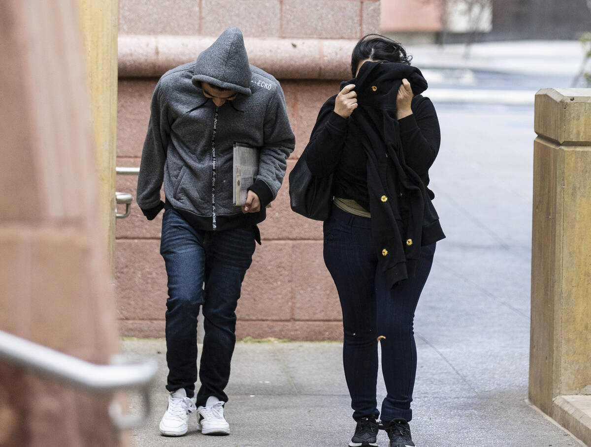 Pedestrians shield their face from the wind as they enter the Regional Justice Center on Thursd ...