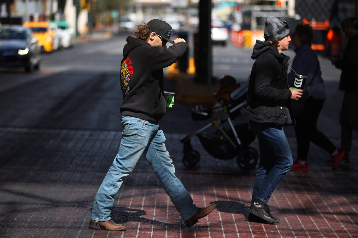 People walk on Fremont Street in Las Vegas during a windy day, Thursday, March 10, 2022. (Erik ...
