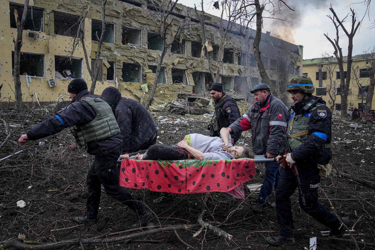 Ukrainian emergency employees and volunteers carry an injured pregnant woman from the damaged b ...