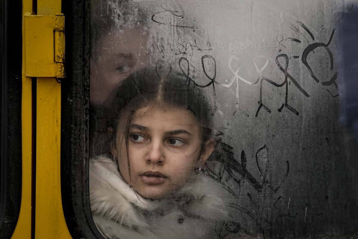A child looks out a steamy bus window with drawings on it as civilians are evacuated from Irpin ...