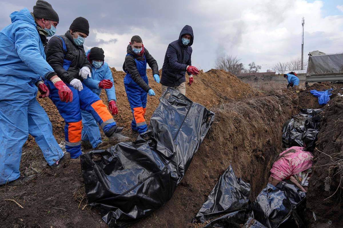 Dead bodies are placed into a mass grave on the outskirts of Mariupol, Ukraine, Wednesday, Marc ...