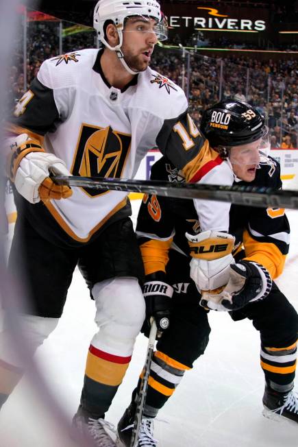 Vegas Golden Knights' Nicolas Hague (14) clears the puck while holding off Pittsburgh Penguins' ...