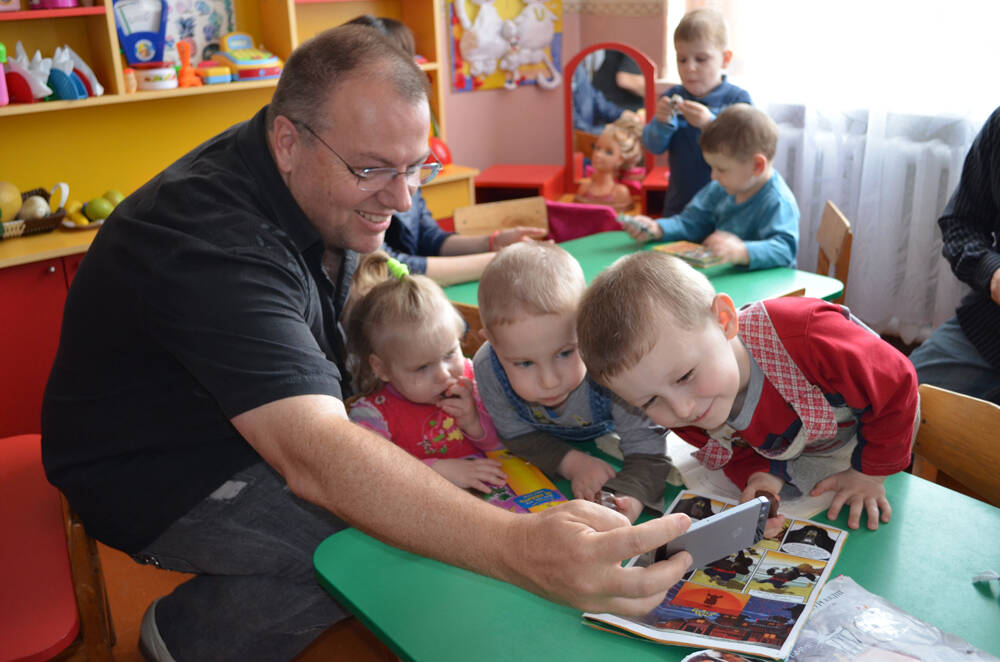 Mark Davis, founder of the nonprofit Abundance International, shows children his phone in a Ukr ...