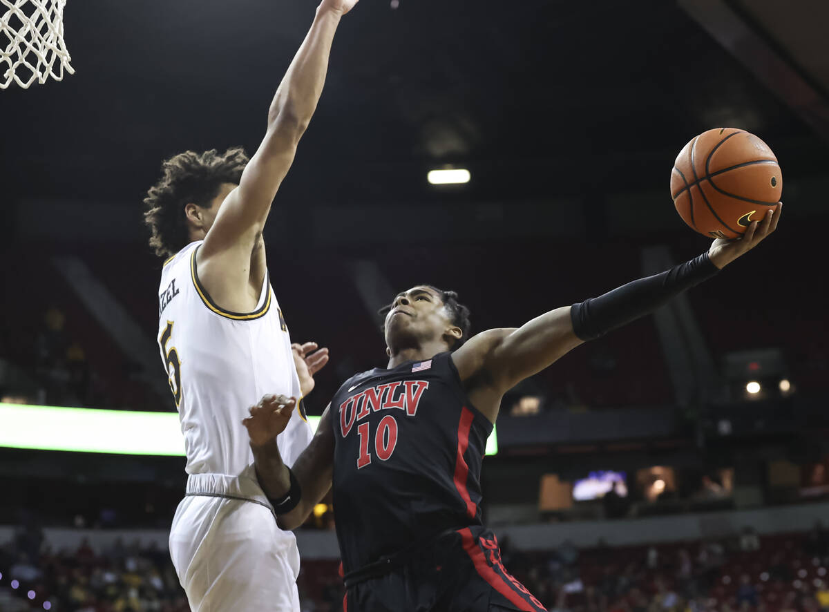 UNLV Rebels guard Keshon Gilbert (10) shoots around Wyoming Cowboys guard Brendan Wenzel (5) du ...