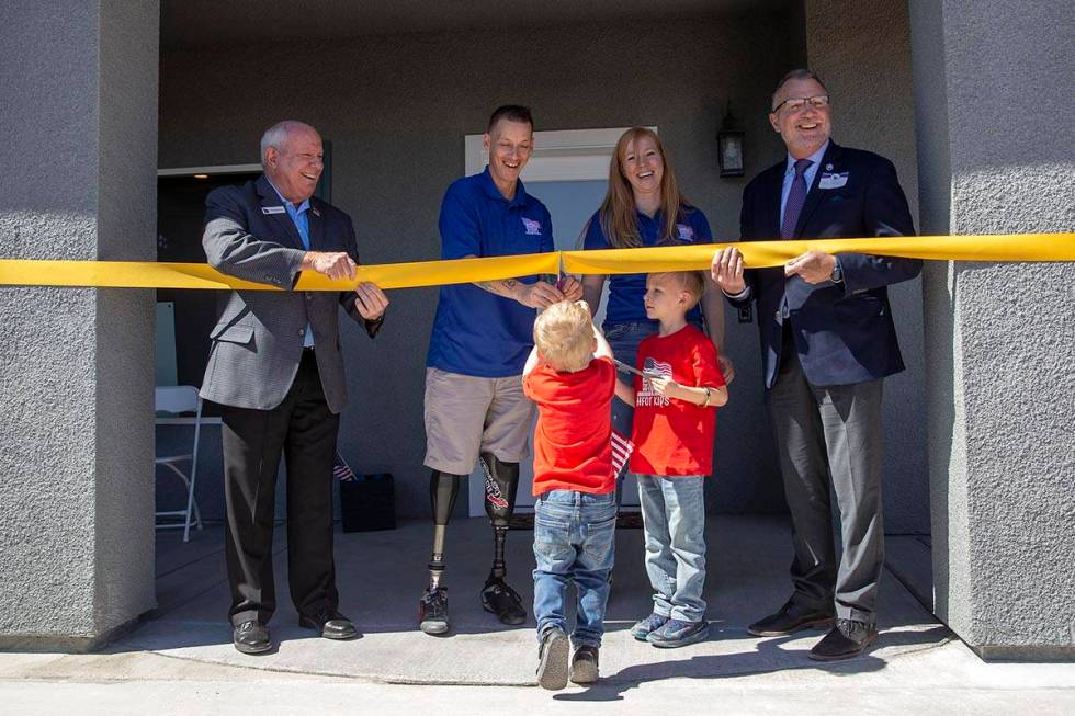 Army Sergeant Adam Poppenhouse and his family cut the ribbon in front of their new home donated ...