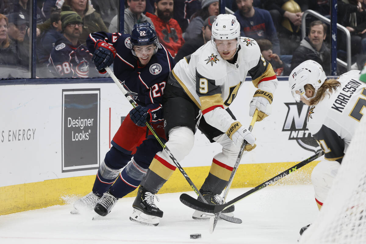 Columbus Blue Jackets' Jake Bean, left, and Vegas Golden Knights' Jack Eichel fight for the puc ...