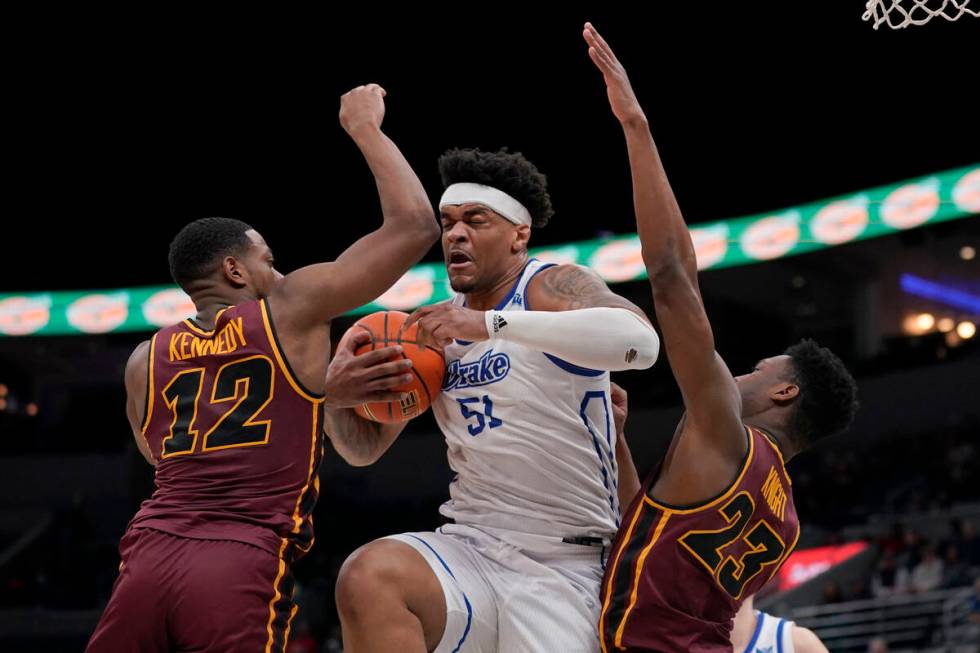 Drake's Darnell Brodie (51) pulls down a rebound as Loyola of Chicago's Marquise Kennedy (12) a ...