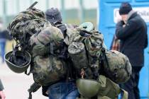 FILE - A man carries combat gear as he leaves Poland to fight in Ukraine, at the border crossin ...