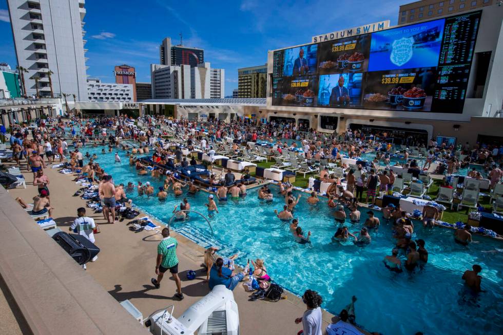The pools and decks are crowded at Stadium Swim as March Madness is projected above at the Circ ...