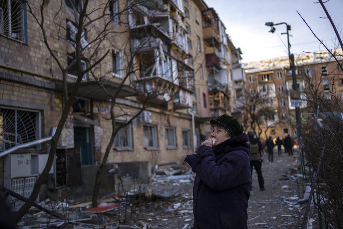 A woman looks at residential buildings damaged by a bomb in Kyiv, Ukraine, Friday, March 18, 20 ...