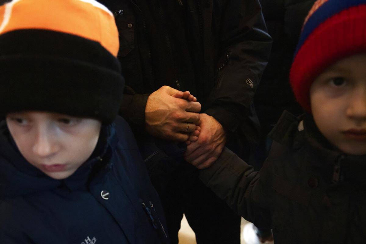 A man from Ukraine holds his sons' hands after arriving at Nyugati station in Budapest, Hungary ...