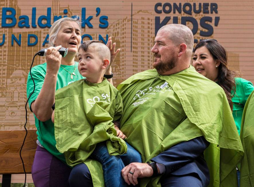 Barber coordinator Anna Duke, top/left, shaves the head of Cayden Creazzo, 4, and father Anthon ...