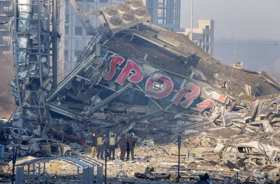 People examine the damage after shelling of a shopping center, in Kyiv, Ukraine, Monday, March ...