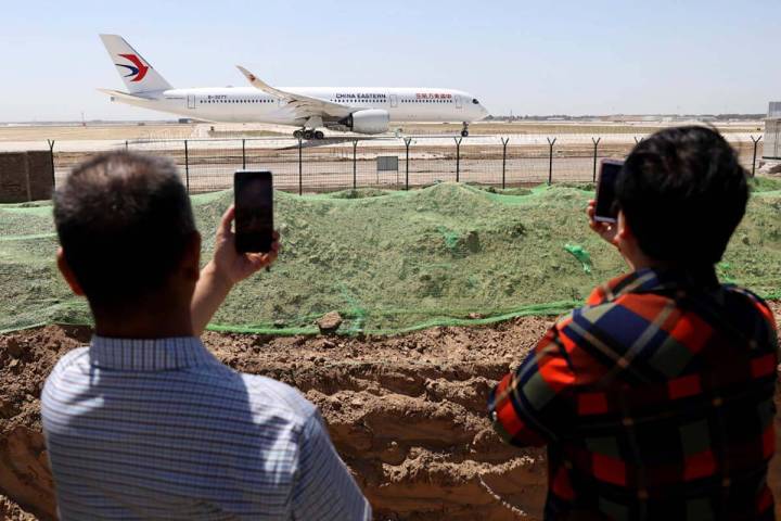FILE - Residents watch as a China Eastern passenger jet prepares to take off on a test flight f ...