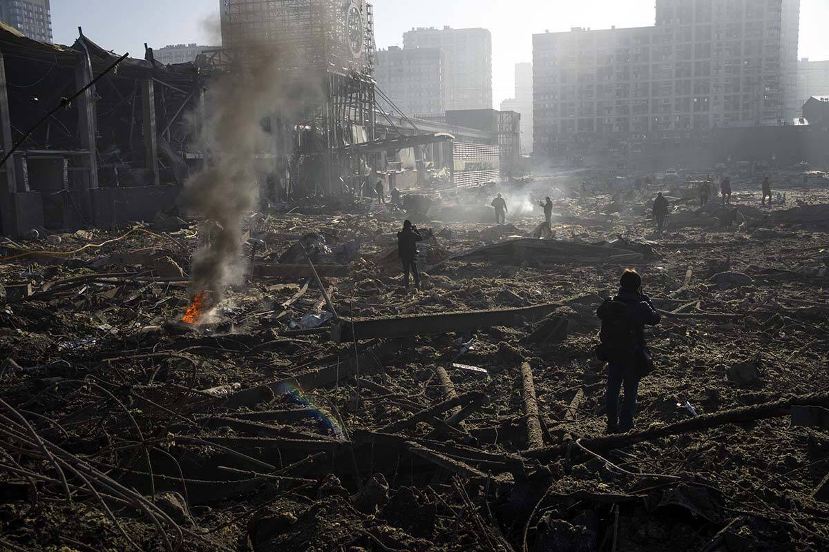 People gather amid the destruction caused after shelling of a shopping center, in Kyiv, Ukraine ...
