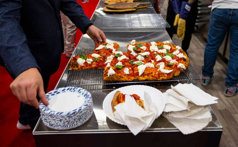 Attendees grab slices of pizza at the Marra Forni Brick Oven Cooking Solutions booth during the ...