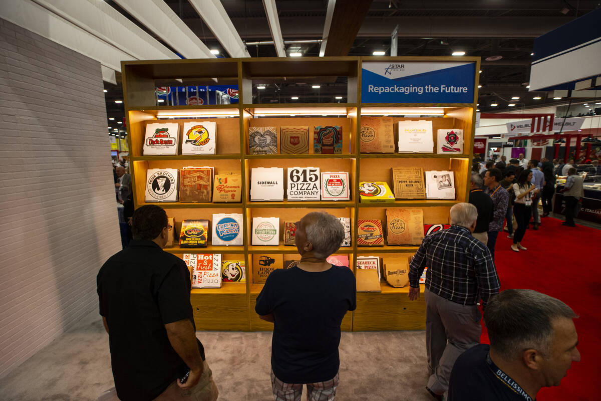 Attendees pass by a display of different pizza boxes during the International Pizza Expo at the ...