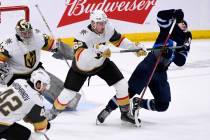 Winnipeg Jets' Adam Brooks (77) gets a stick up in his jersey from Vegas Golden Knights' Zachar ...