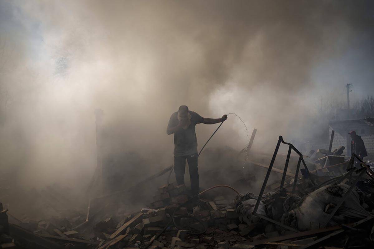 Neighbours try to extinguish the fire of a house, destroyed after a Russian attack in Kharkiv, ...