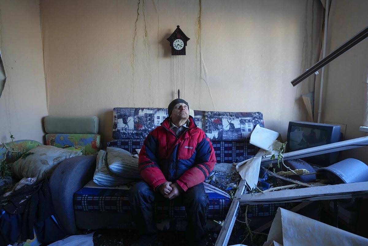 A man looks up as he sits in his apartment in a multistory house destroyed by a Russian attack ...