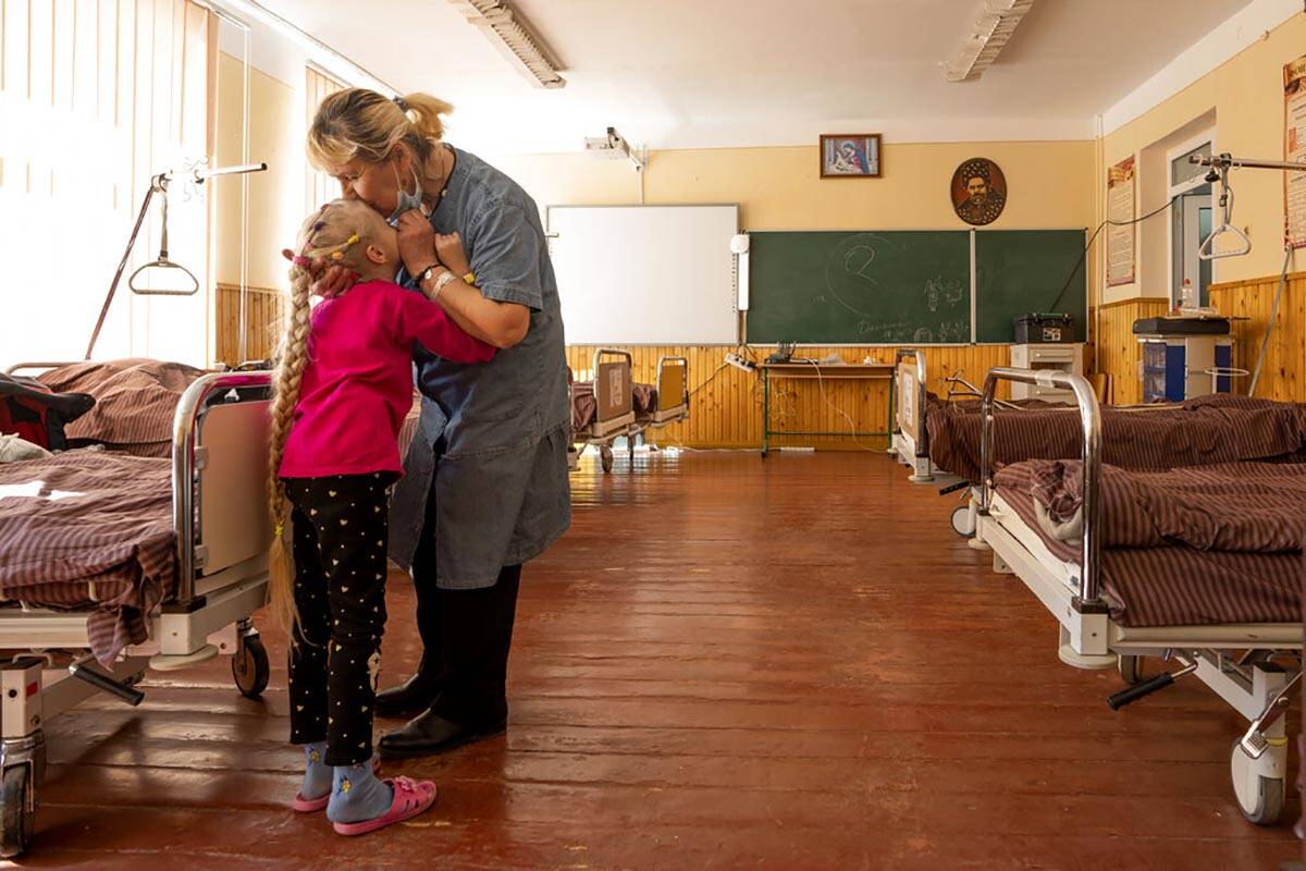 Nadia kisses her 10-year-old granddaughter Zlata Moiseinko, suffering from a chronic heart cond ...